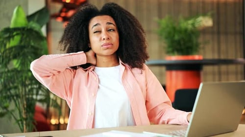 African American Businesswoman with Neck Pain While Working on Laptop in Office