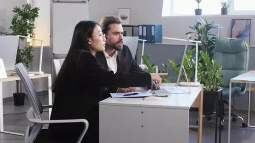 Colleagues Showing Graphics on Desktop Computer in Office