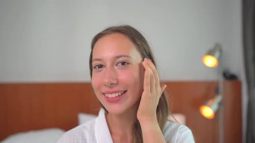 Beautiful Woman Applying Cream to Her Face, Smiling
