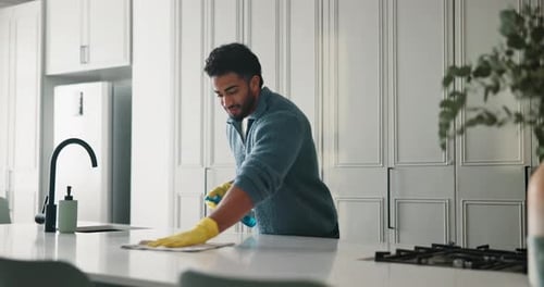 Man in Kitchen Cleaning Countertop with Spray and Cloth