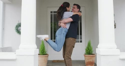 Vídeo em 4K de um jovem casal feliz se abraçando na entrada de sua casa