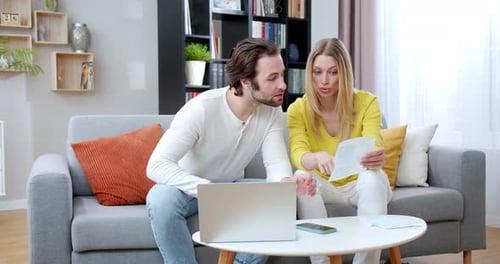 Couple Reviewing Finances Together at Home Using Laptop