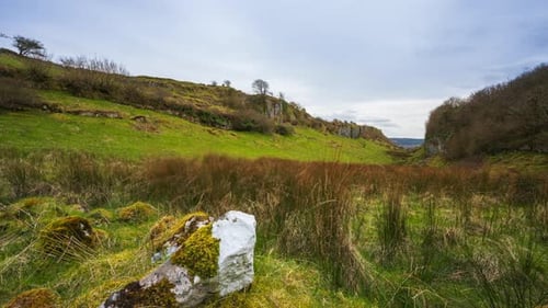 Timelapse of rural nature farmland with rock stone in grass field during cloudy day viewed from Carr