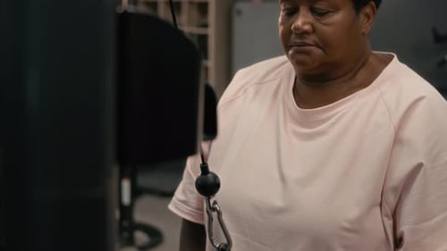 Concentrated Senior Black Woman Working Out Using Gym Equipment