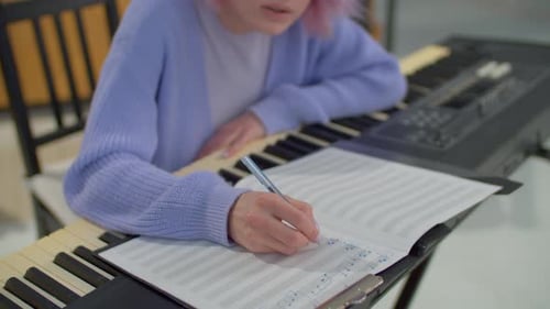 Musician Playing Keyboard and Writing Music