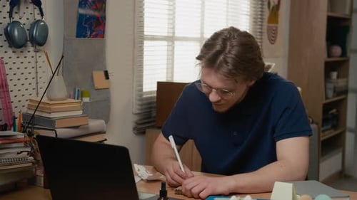 Portrait of Male Student Studying at Desk and Smiling at Camera