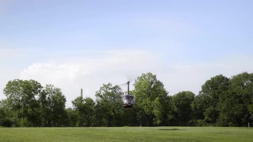 Wide shot of helicopter taking off in middle of field.