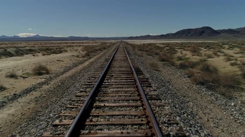 Niedrige, zurückziehende Luftaufnahme von geraden Eisenbahnschienen in der Wüste