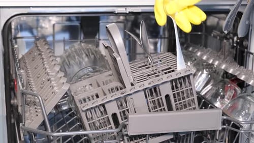 A Woman Arranges Dishes in the Dishwasher for Automatic Washing to Make Household Chores Easier