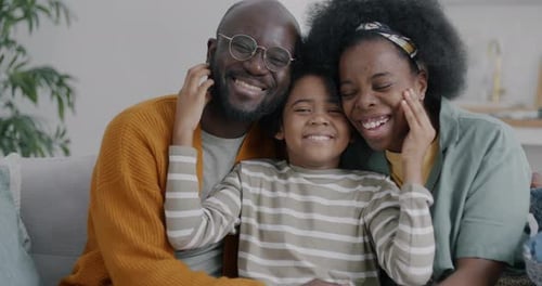 Happy Family Smiles Together on Sofa At Home