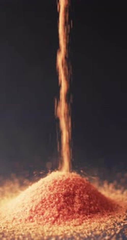Vertical video of close up of heap of red sand grains and copy space on black background
