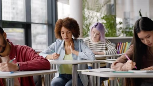 Zeitlupe einer Studentin, die während einer Schulprüfung einen Test von einer Klassenkameradin abschreibt