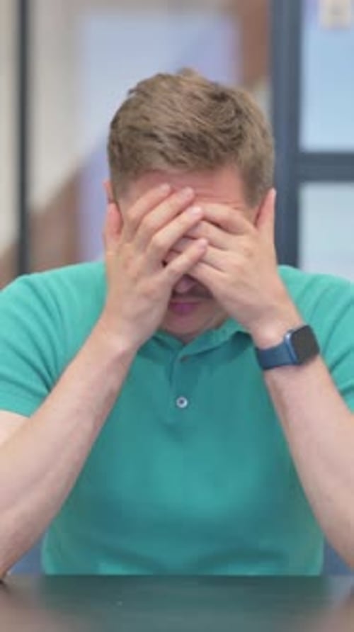 Vidéo verticale d'un homme adulte mature déprimé souffrant de migraine au bureau