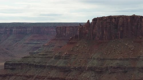 A high-flying drone shot of massive plateaus of colorful rock, and its steep layered cliffs, in a re