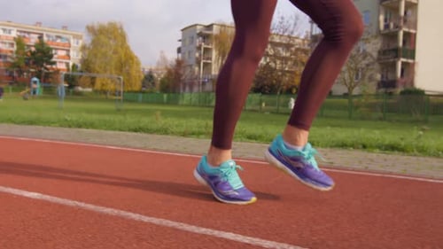 View of the legs of a girl in running shoes warming up for a run on a running track in slow motion