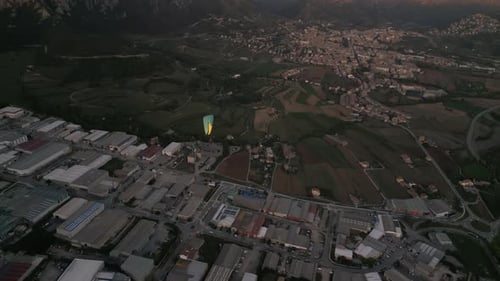 Aerial Shot Following a Paraglider Flying Above the Green Forest and Countryside