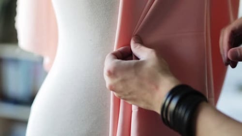 Fashion designer creating a bespoke dress with cloth and pins in a studio
