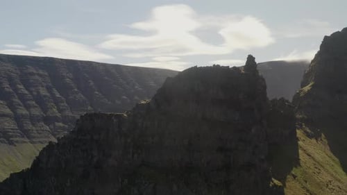 Flying up and over the peak of Svalvogar mountain in the Western Fjords of Iceland on a sunny summer