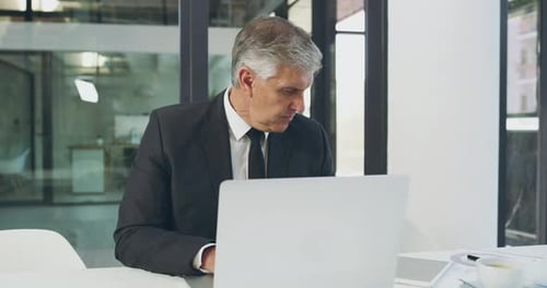 4k video footage of a handsome mature businessman working on a laptop in his office