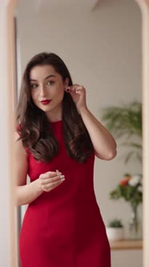 Stylish Woman Puts on Earrings in Front of Mirror