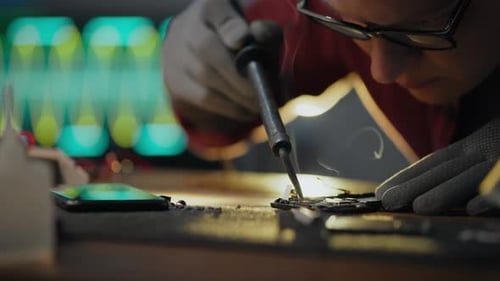 Adult repairing electronics with a soldering iron