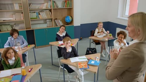 Elementary School Class Children Communicate with the Teacher Answering Question