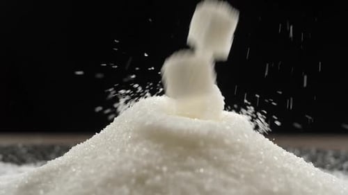 Zuckerwürfel fallen auf einen Zuckerhaufen