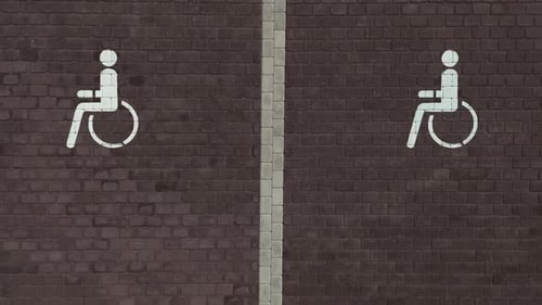 Two Wheelchair Signs Depicted on Brick Wall in Artful Font