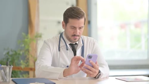 Male Doctor Using Smartphone in Clinic