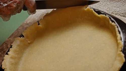 Cutting Pie Crust Dough with Knife in Kitchen