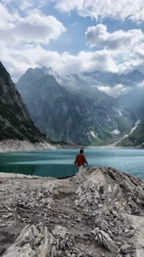 Man Exploring a Stunning Alpine Lake in the Mountains