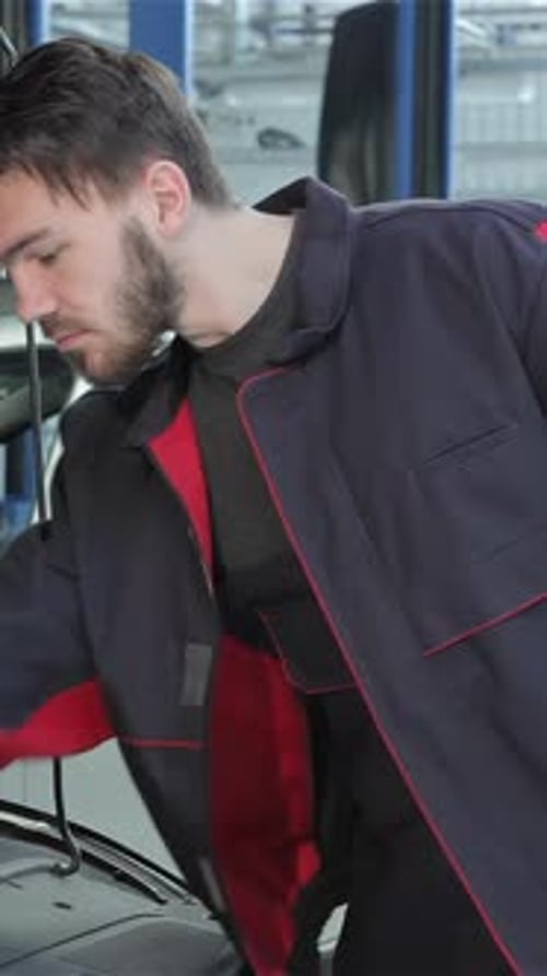 Dedicated Mechanic Inspects Car Engine with Precision at Service Station