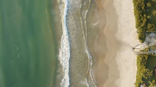Beautiful drone cinematic top view panning over the ocean of a brazilian beach with white sand and e