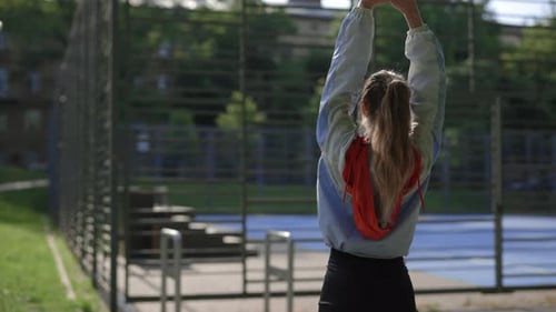Back View of Young Caucasian Woman Stretching Her Back Before Running