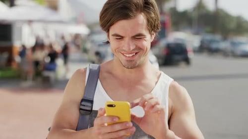 Smiling Man Uses Phone on Urban Street