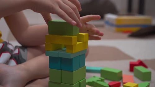 The child builds an imaginary tower of wooden multi-colored cubes