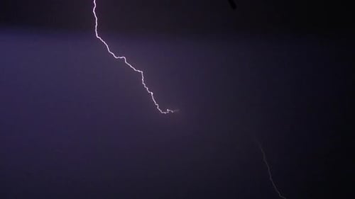 Flashes of lightning in the night sky among thunderclouds.