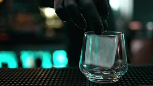 Gloved Hand Places Ice Cube into Glass