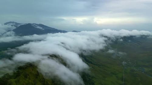 Fliegen Sie durch Regenwolken über grünen Berggipfeln, die von tropischem Dschungel bedeckt sind
