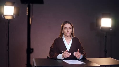 Woman Speaking at Desk in Studio with Lighting