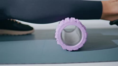Closeup Sportswoman Using Massaging Roller Doing Fitness Workout in Light Gym