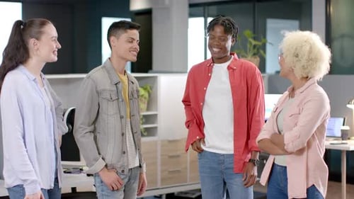 Smiling group of diverse colleagues standing together in modern office workspace