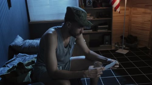 Contemplative Young Man Looking at Photograph with Drink