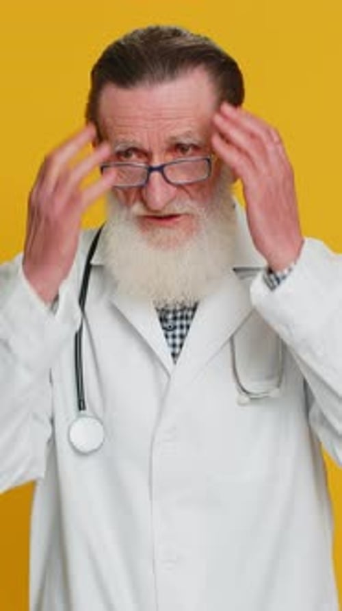 Senior doctor expressing worry and anxiety on yellow background
