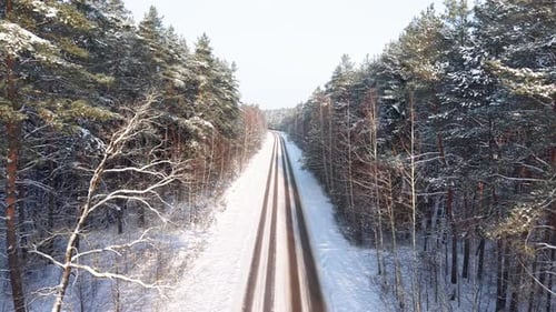 Aerial View of Snowy Forested Road in Winter Landscape