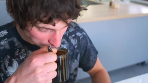 Young Adult Drinking from Mug and Using Tablet