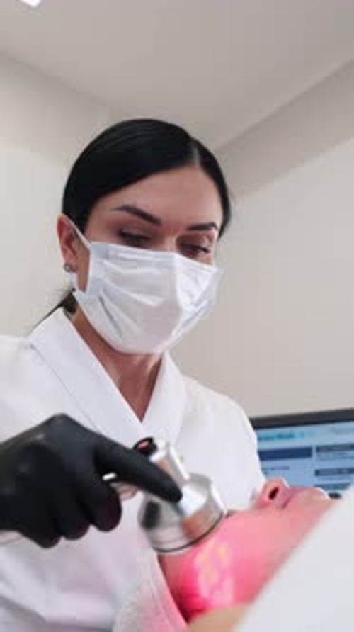 Woman Performing Face Treatment with Small Device