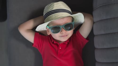 Child with Sunglasses Lying Down on Couch