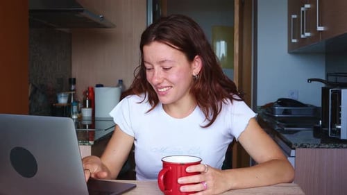 Young Woman Working on Laptop in Kitchen