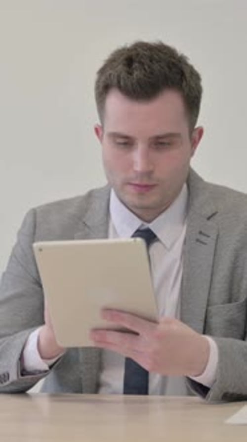 Man in Suit Uses Tablet in Clean Setting